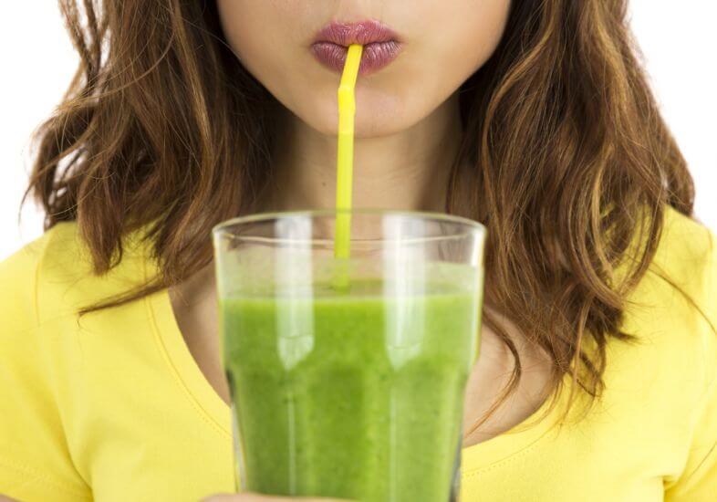 Dieta à base de suco detox Mulher bebendo suco detox em um copo com canudo