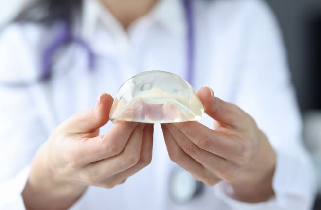 mulher segurando prótese de silicone rompida