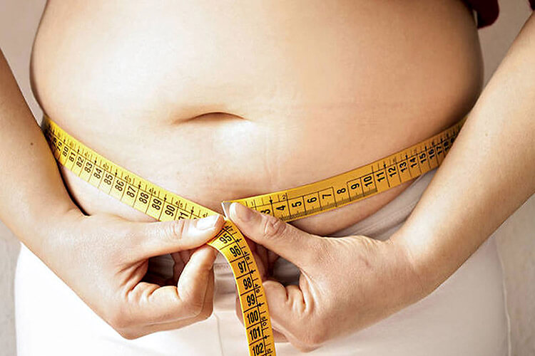 mulher segurando fita métrica em torno da barriga