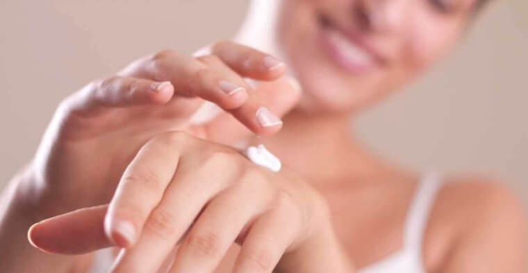 Cuidados com a pele do pescoço e das mãos Mulher aplicando cremes para prevenir envelhecimento da pele das mãos